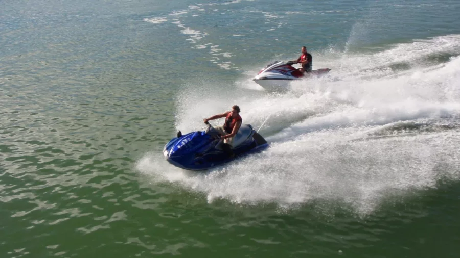 Two people riding jet skis side by side in the Bay of Islands