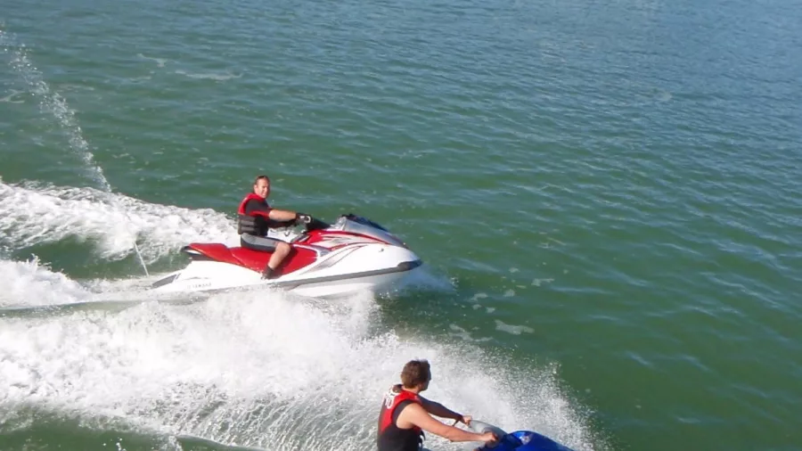 Two people riding jet skis side by side in the Bay of Islands
