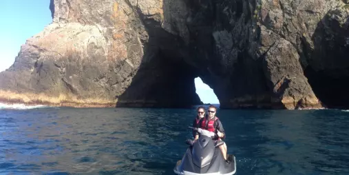 Jet-ski passing through the Hole in the Rock along New Zealand’s Whakaari/White Island coast