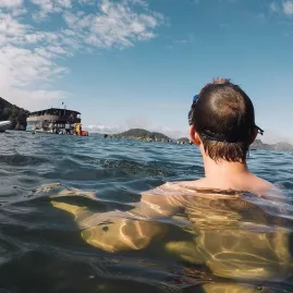 Snorkeller in the Bay of Islands looking back at The Rock Adventure Cruise vessel