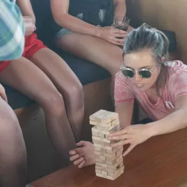 Woman playing Jenga with friends onboard The Rock boat in the Bay of Islands
