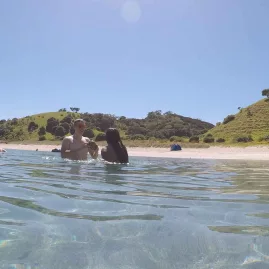 People swimming in clear waters of the Bay of Islands