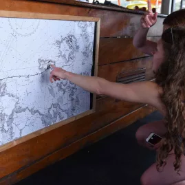 Two people examining a nautical map onboard The Rock Adventure Cruise in the Bay of Islands
