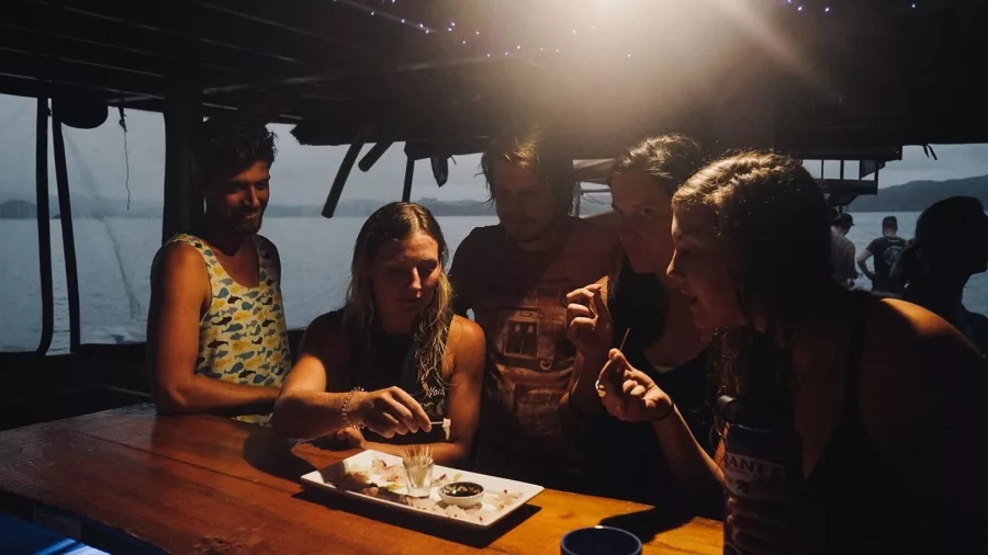 Travellers enjoying snacks and drinks on board during The Rock Adventure Cruise in the Bay of Islands