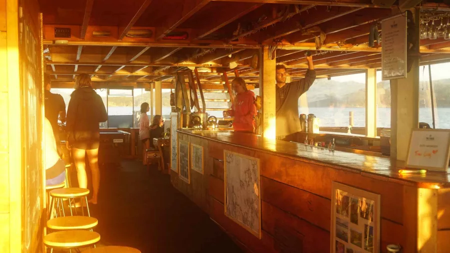 Guests relaxing on the boat deck of The Rock Adventure Cruise during golden hour in the Bay of Islands