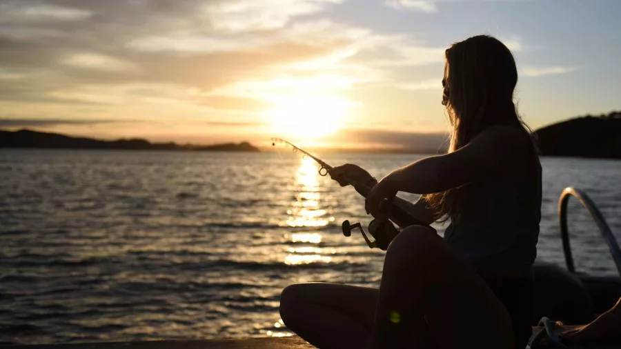 Woman fishing at sunset on The Rock Adventure Cruise in Bay of Islands