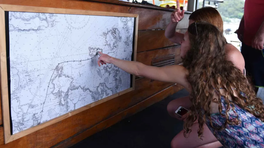 Two people examining a nautical map onboard The Rock Adventure Cruise in the Bay of Islands