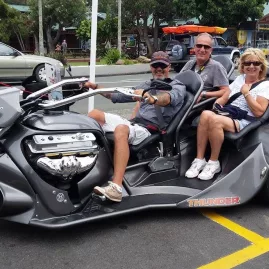 Three people seated on a Thunder Trike parked in a Bay of Islands town centre
