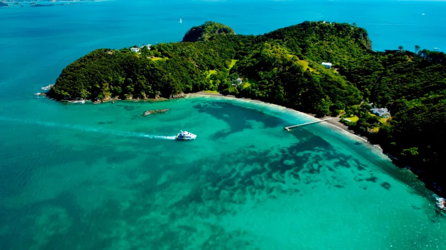 Aerial view of a boat approaching Otehei Bay on Urupukapuka Island surrounded by turquoise waters