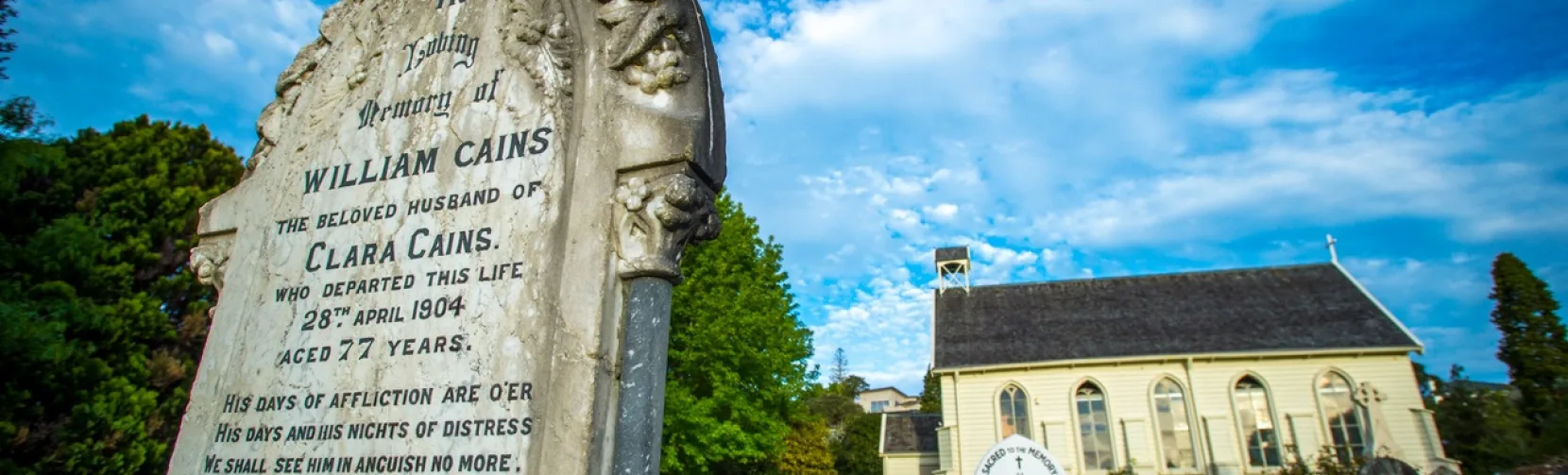 Gravestones in the churchyard of Christ Church in Russell, New Zealand’s oldest church, under a bright blue sky