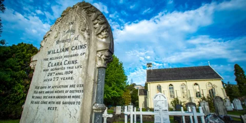 Gravestones in the churchyard of Christ Church in Russell, New Zealand’s oldest church, under a bright blue sky