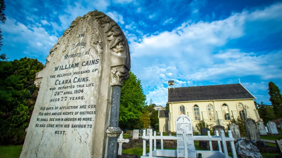 Gravestones in the churchyard of Christ Church in Russell, New Zealand’s oldest church, under a bright blue sky