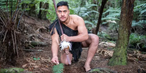 Māori warrior performing the wero challenge in the forest at Waitangi Treaty Grounds, Northland, New Zealand