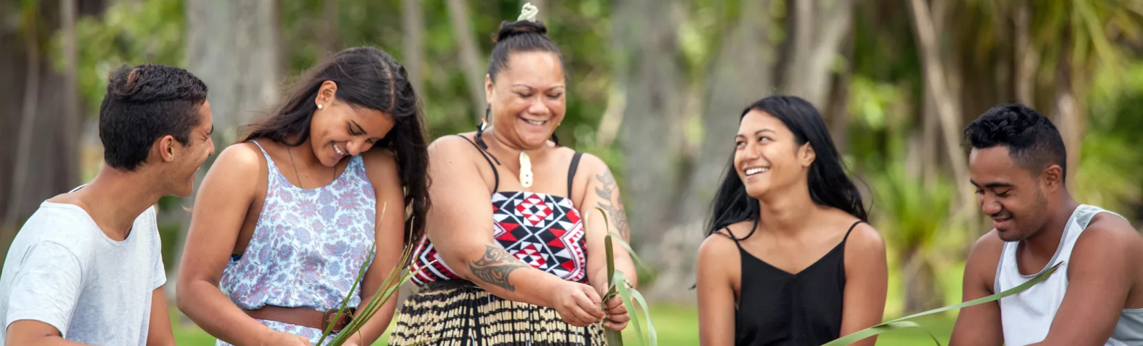 Group learning traditional flax weaving on the lawn at Waitangi Treaty Grounds, Northland, New Zealand