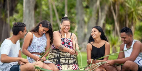 Group learning traditional flax weaving on the lawn at Waitangi Treaty Grounds, Northland, New Zealand