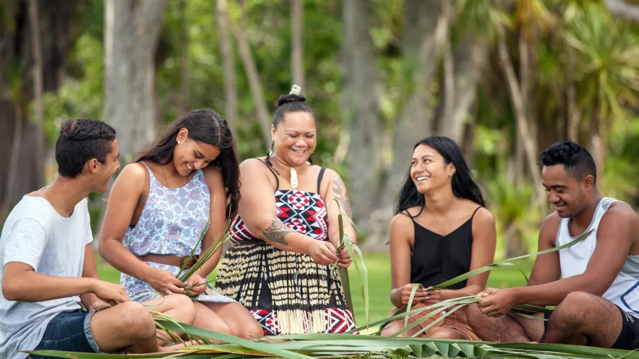 Group learning traditional flax weaving on the lawn at Waitangi Treaty Grounds, Northland, New Zealand