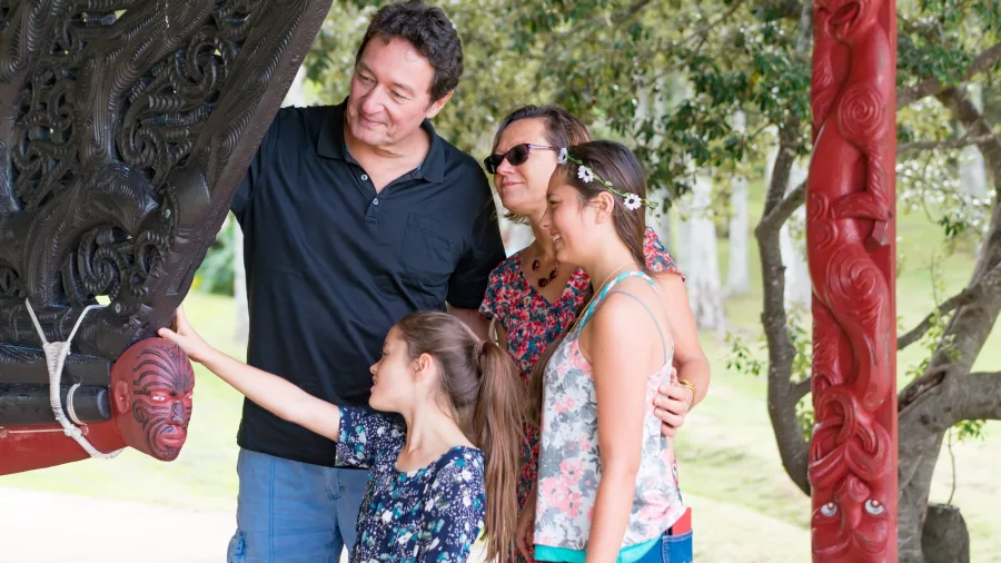Family viewing the detailed carvings on a ceremonial waka at Waitangi Treaty Grounds, Northland, New Zealand