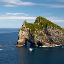 Tour boat approaching the Hole in the Rock at Motukōkako Island in the Bay of Islands
