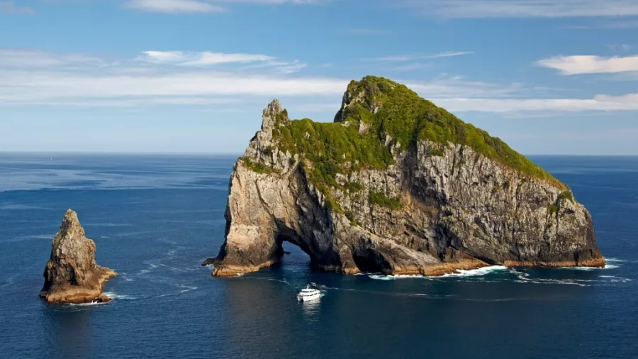 Tour boat approaching the Hole in the Rock at Motukōkako Island in the Bay of Islands