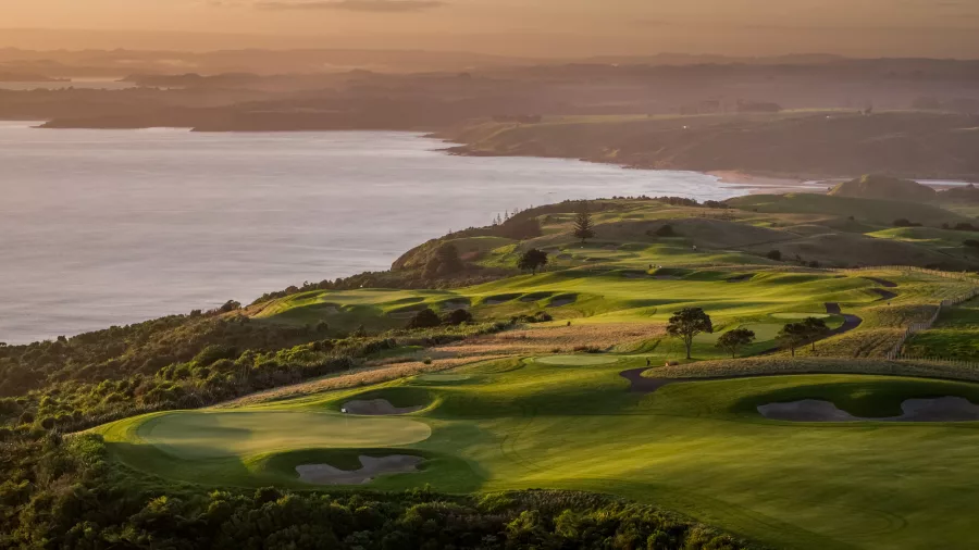 Sunset casting golden light over Kauri Cliffs Golf Course and coastline, Bay of Islands, New Zealand