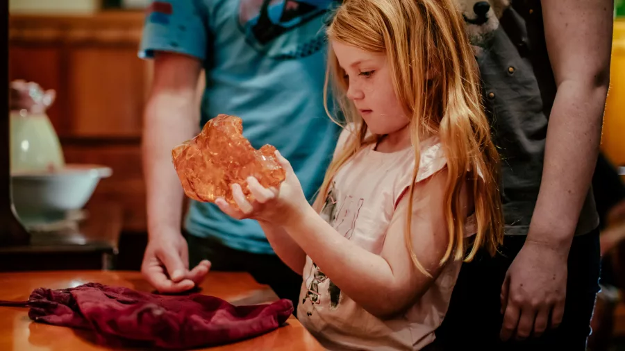 Young girl holding a large piece of kauri gum at The Kauri Museum