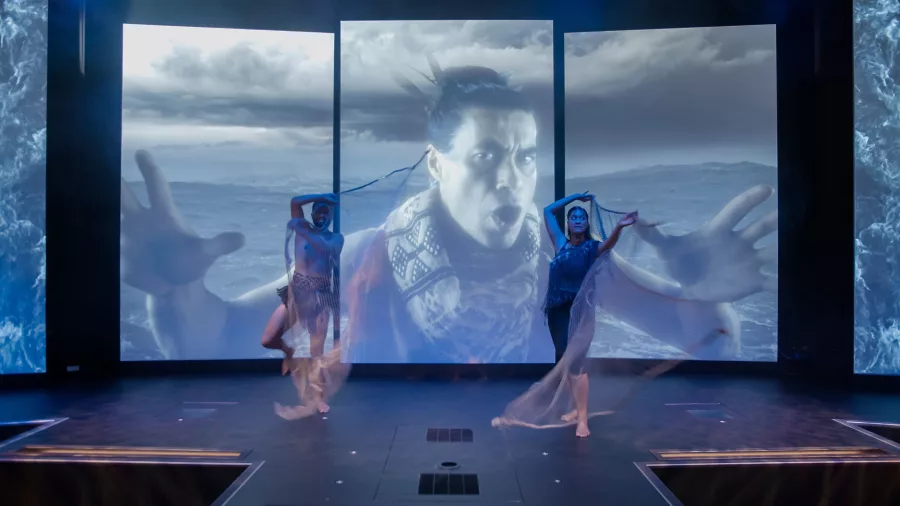 Performers dancing in front of a digital projection at the Manea 4D Theatre during an immersive Māori storytelling experience