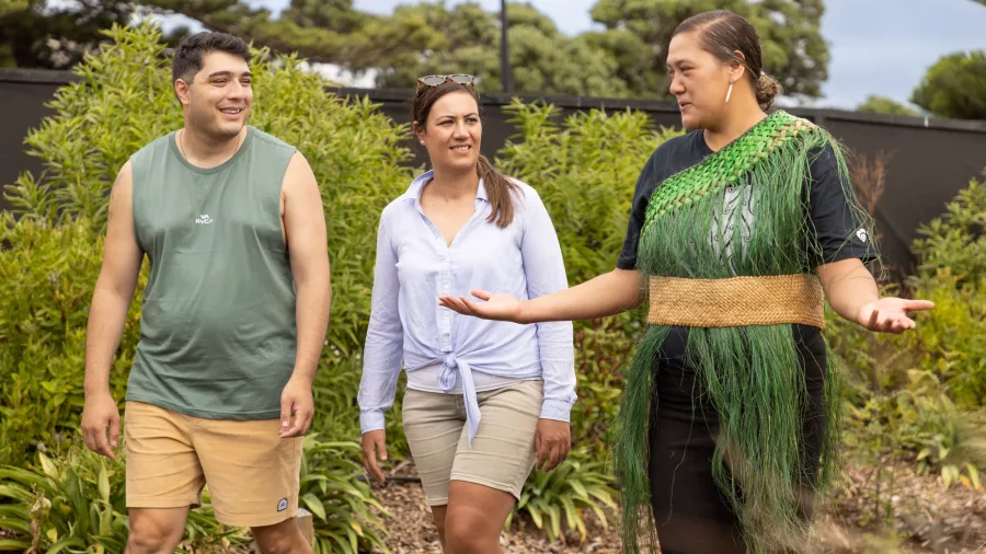 Māori guide leading a walking tour and sharing stories with two visitors at Manea cultural centre in Northland
