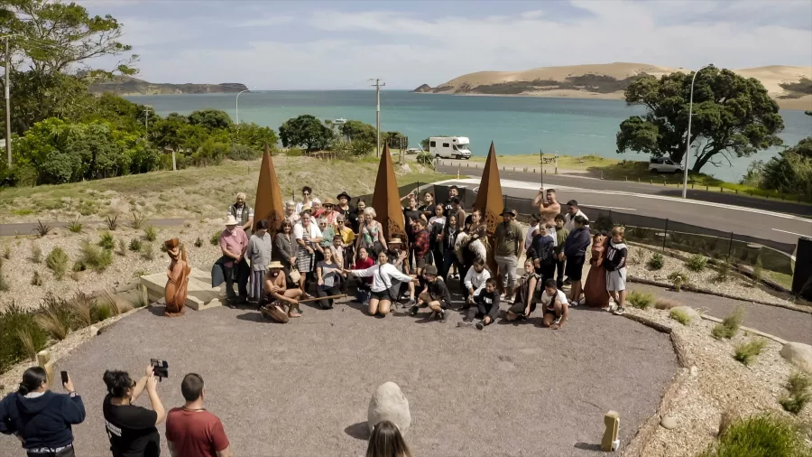 Large group photo taken at Manea Lookout with Hokianga Harbour and sand dunes in the background
