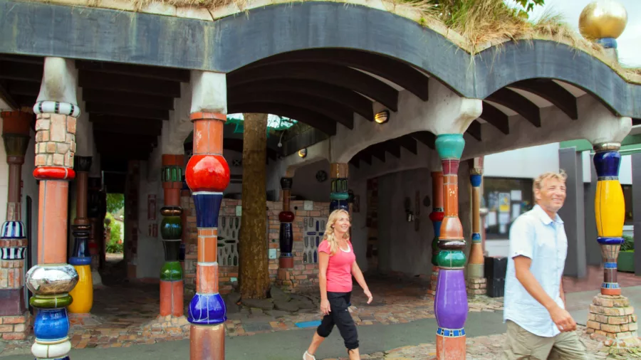 Tourists walking past the colourful and quirky Hundertwasser Toilets in Kawakawa