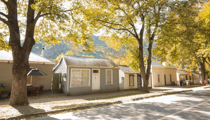 Avenue of historic cottages in Arrowtown surrounded by golden autumn foliage.