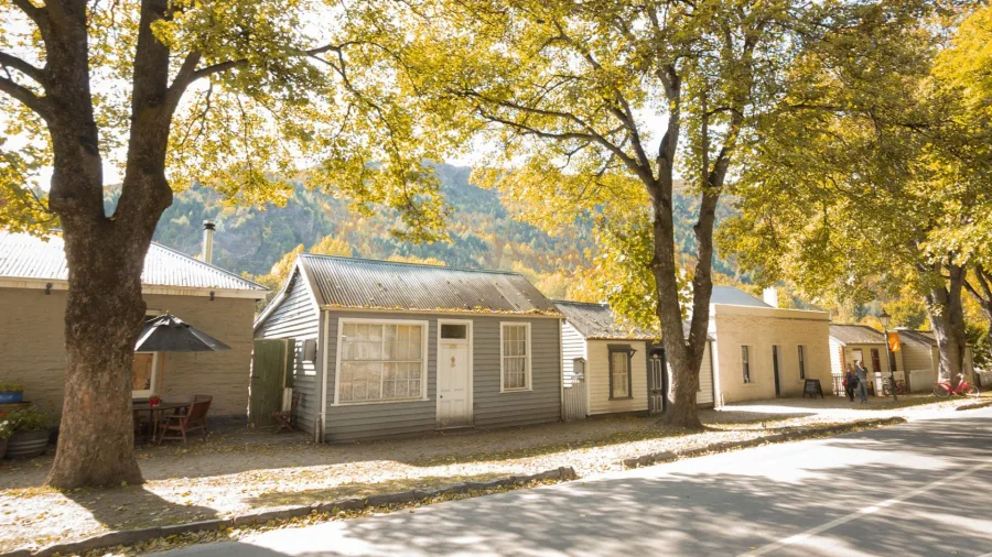 Avenue of historic cottages in Arrowtown surrounded by golden autumn foliage.