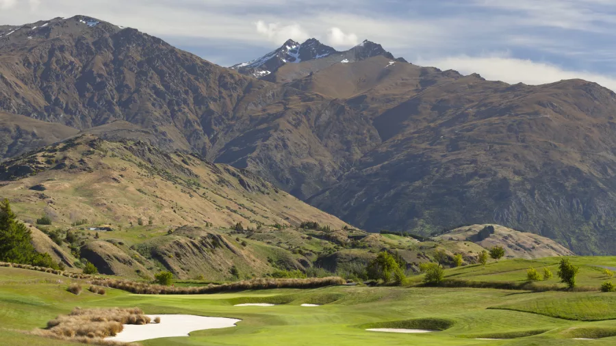 The Hills Golf Course in Arrowtown with lush green fairways, sand bunkers, and dramatic mountain views near Queenstown, New Zealand.