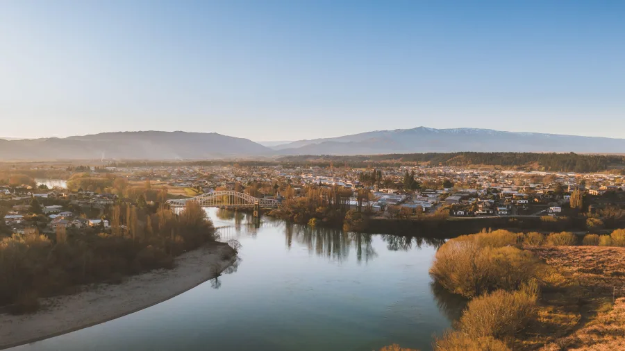 Aerial view of Alexandra Bridge and townscape in Central Otago with river and mountains in the background.