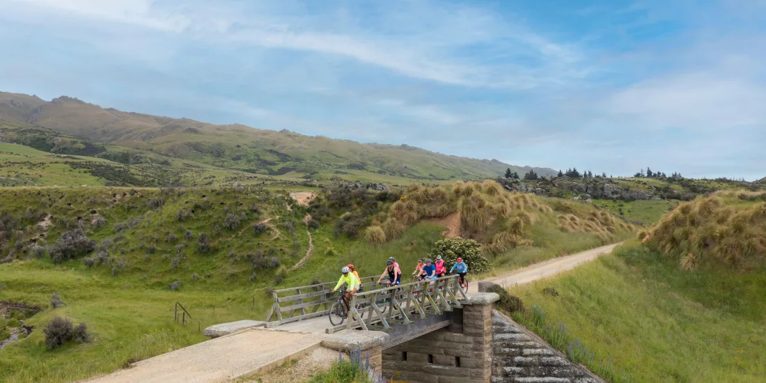 Cyclists silhouetted against blue sky riding across a bridge near Middlemarch on the Otago Central Rail Trail