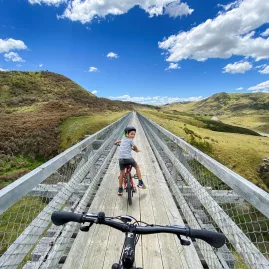 Father photographing young son on single-lane bridge, Otago Central Rail Trail