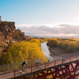 Family cycling across rail trail bridge at sunrise in Central Otago
