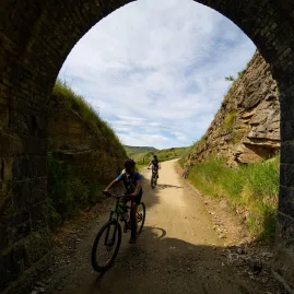 Cyclists entering a historic railway tunnel archway on Otago Central Rail Trail