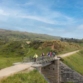 Cyclists silhouetted against blue sky riding across a bridge near Middlemarch on the Otago Central Rail Trail