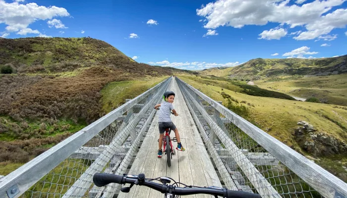 Father photographing young son on single-lane bridge, Otago Central Rail Trail