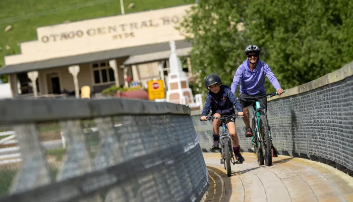 Cyclist and child crossing footbridge at Hyde former railway station on rail trail