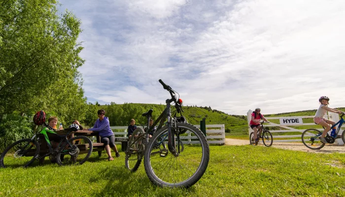 Cyclists and visitors resting beside Otago Central Rail Trail at Hyde trailhead