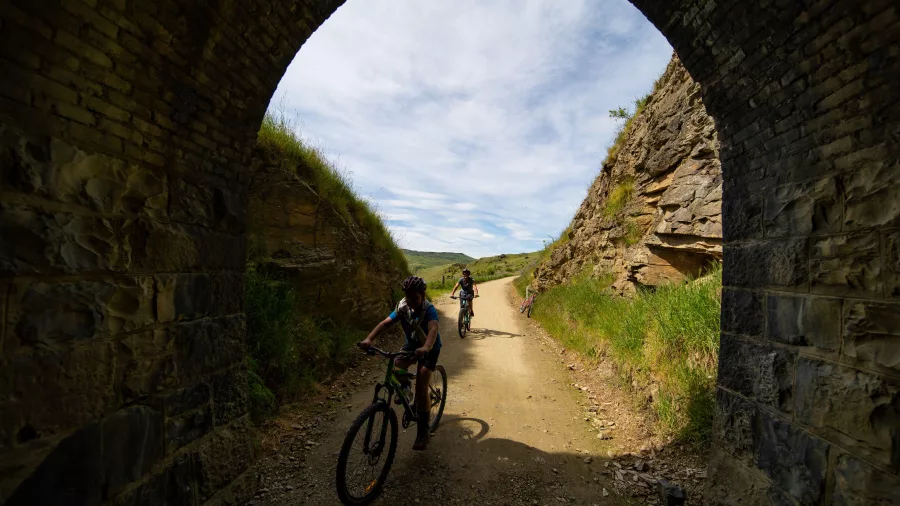 Cyclists entering a historic railway tunnel archway on Otago Central Rail Trail