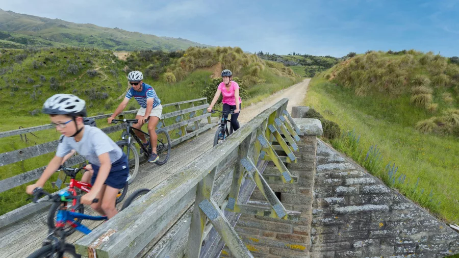 Family riding bikes across wooden bridge near Middlemarch on the Otago Central Rail Trail