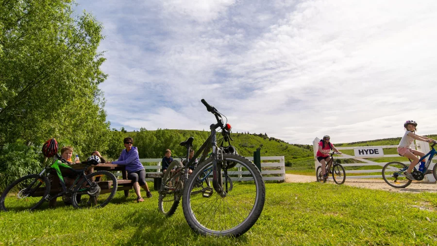 Cyclists and visitors resting beside Otago Central Rail Trail at Hyde trailhead