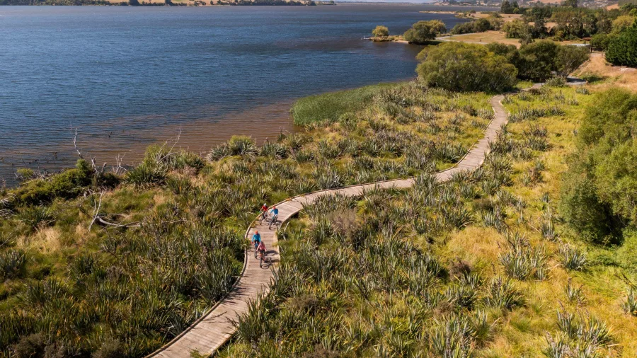 Cyclists riding along a boardwalk section of the Clutha Gold Trail extension between Lawrence and Milton in Central Otago, New Zealand