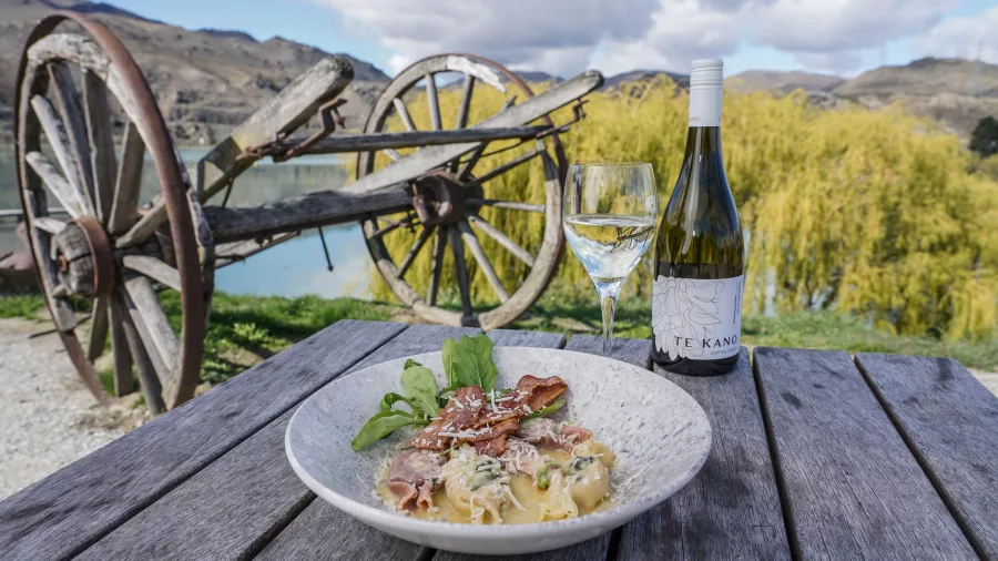 Gourmet meal with a glass of Te Kano white wine served outdoors at Armando’s Kitchen in Cromwell, Central Otago, New Zealand