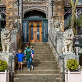 A mother and child walking down the stone staircase at the entrance of Larnach Castle in Dunedin.