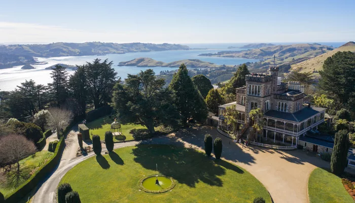 Aerial view of Larnach Castle with Otago Peninsula coastline in the distance.