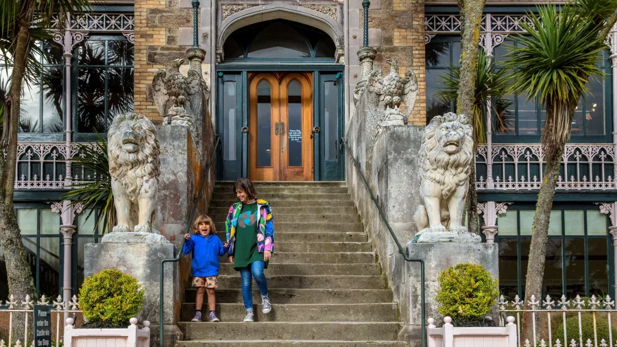 A mother and child walking down the stone staircase at the entrance of Larnach Castle in Dunedin.