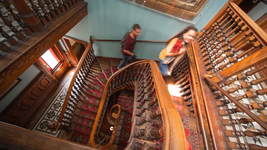 Visitors walking up the grand wooden staircase inside Larnach Castle.